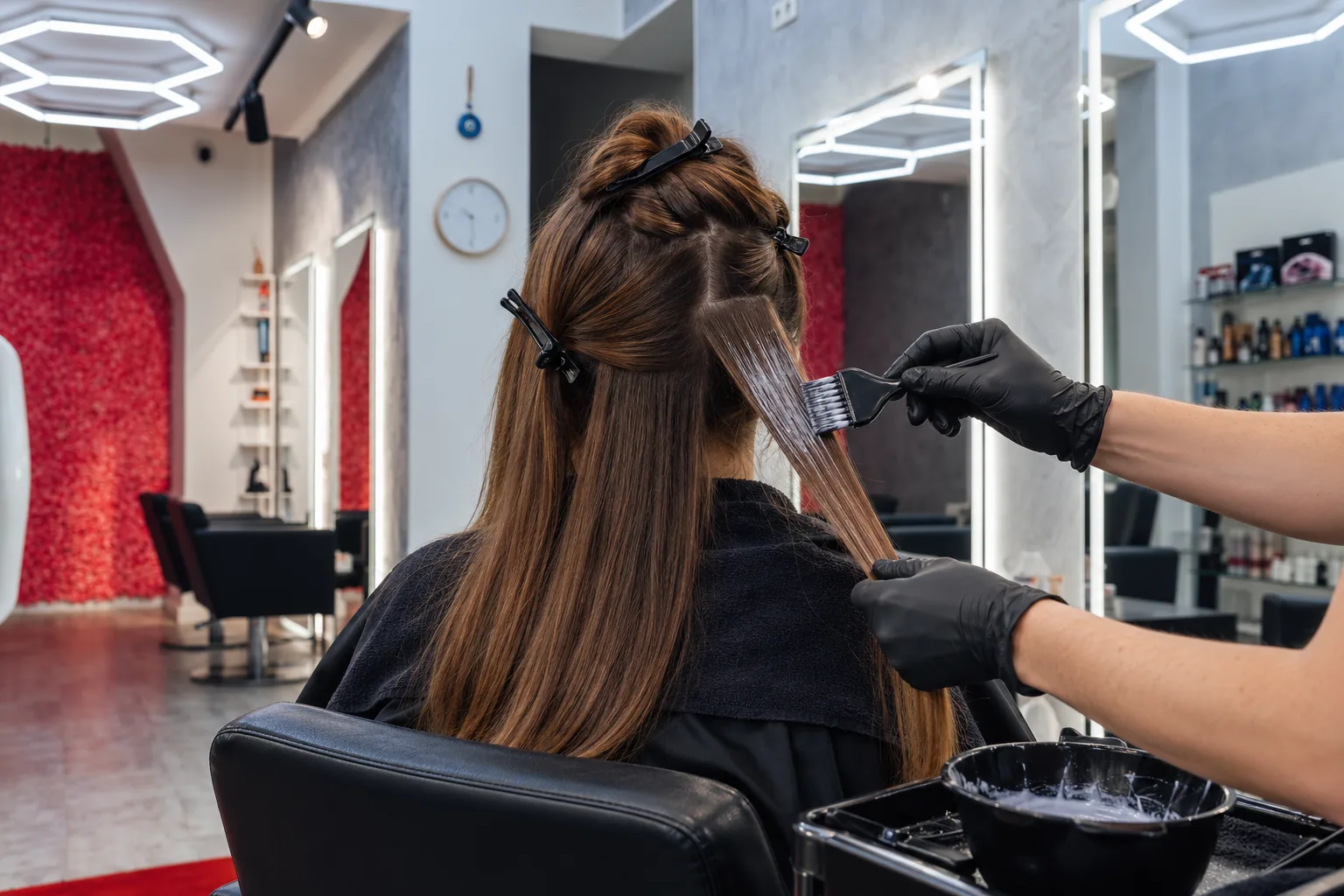 Professioneller Auftrag einer Keratin-Behandlung auf sorgfältig abgeteiltes Haar im Headmasters Salon